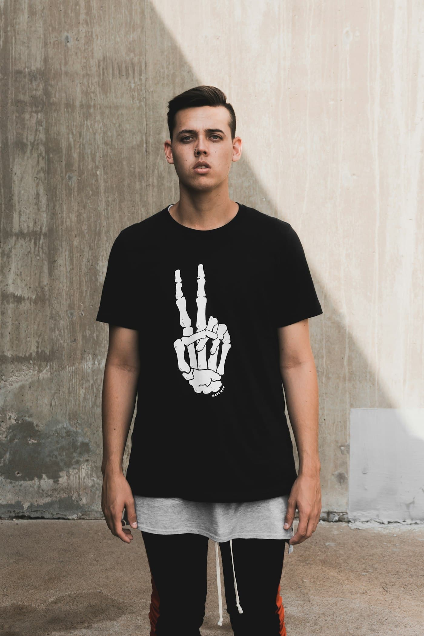Creator wearing a graphic tee against a concrete wall